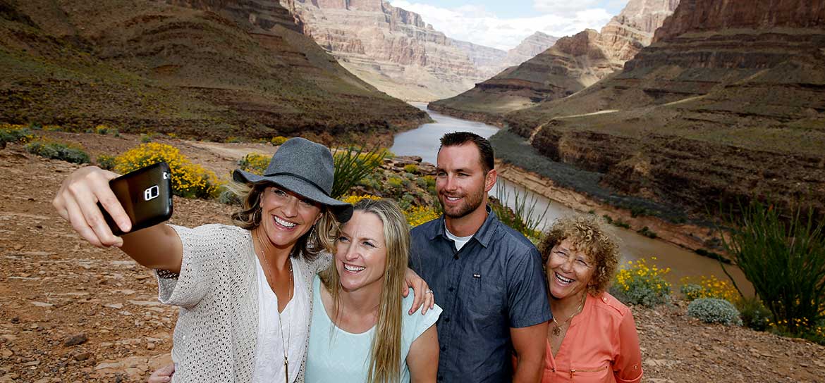 Four people pose for a photo on the floor of the Grand Canyon