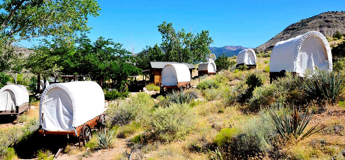 Several covered wagons scattered throughout a desert landscape