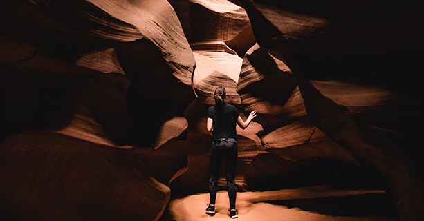 A visitor stands inside a narrow slot canyon.