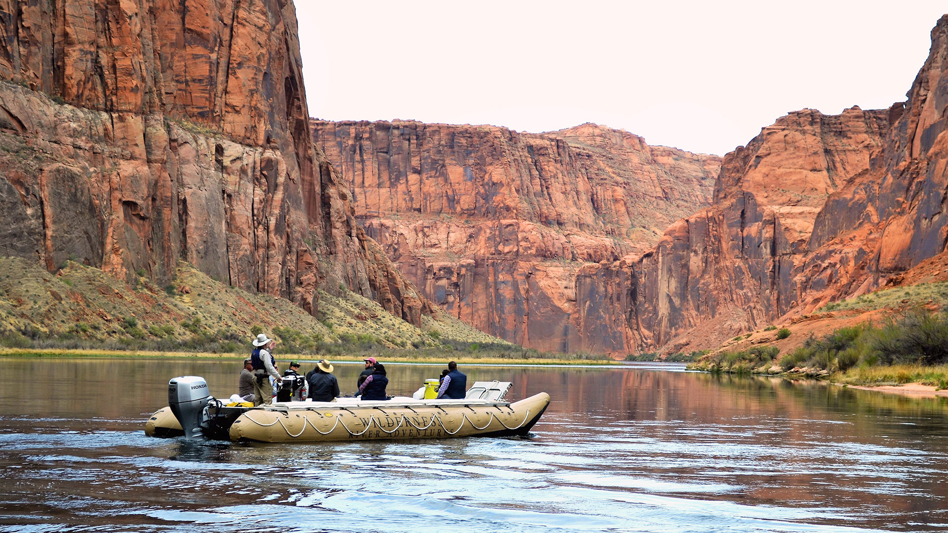 Passengers aboard a large raft float down the Colorado River.