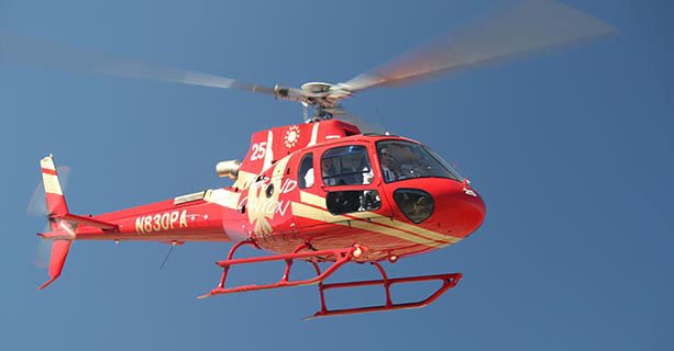 A helicopter in flight over a clear blue sky.