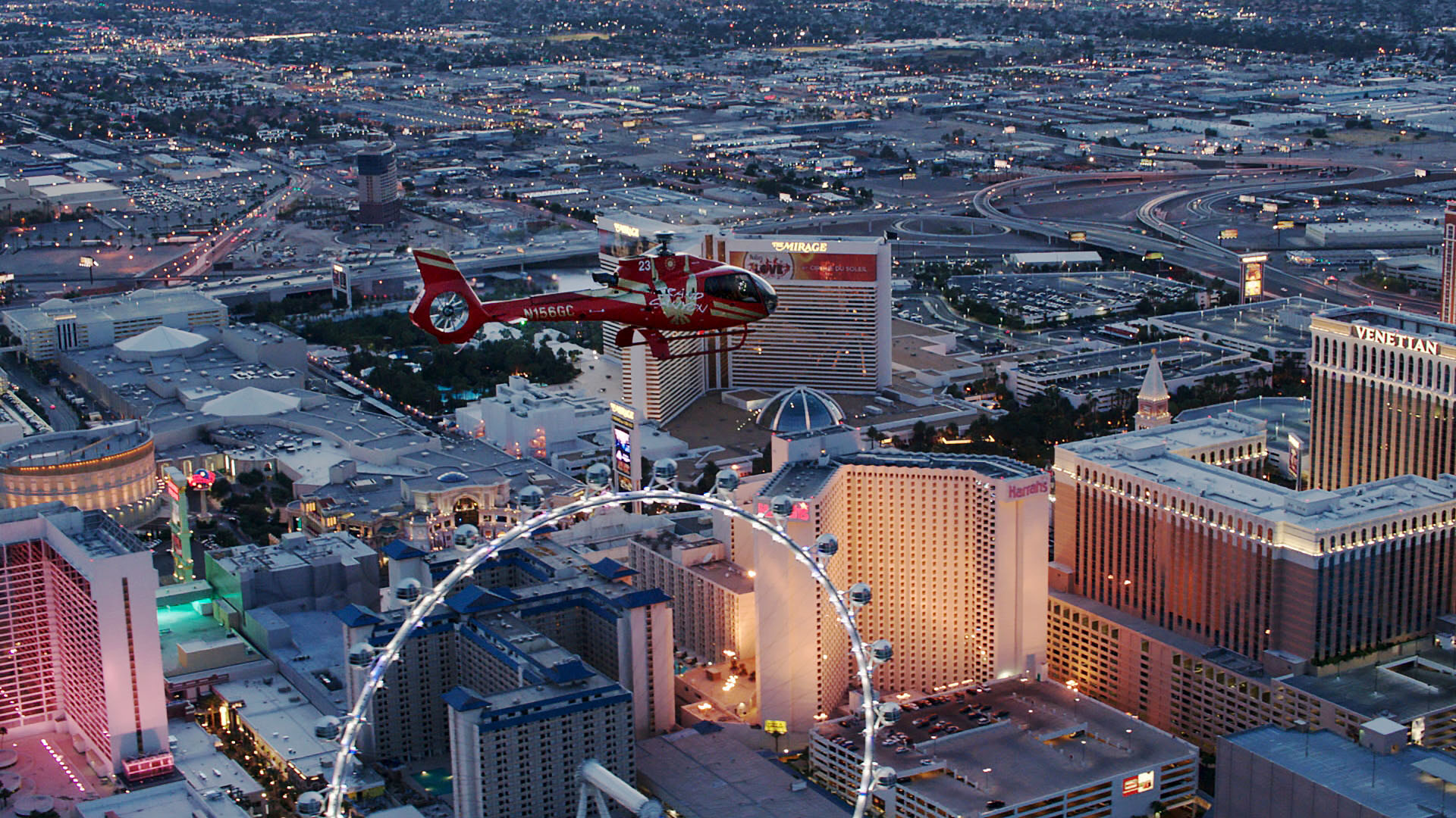 A red helicopter flies over the ferris wheel on the Las Vegas Strip.