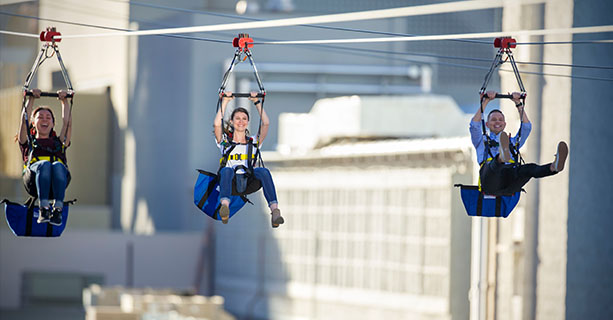 Three people mid-flight on a zipline.