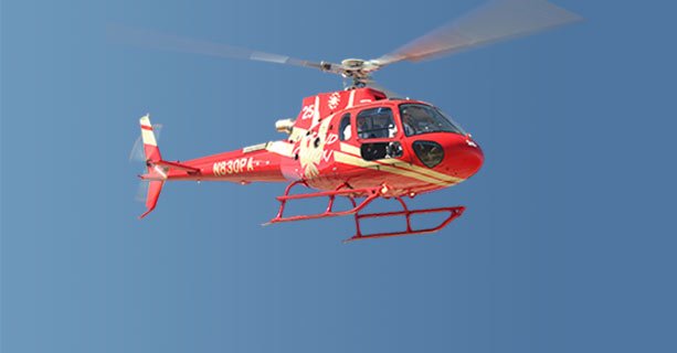 A helicopter hovering in a bright blue desert sky.