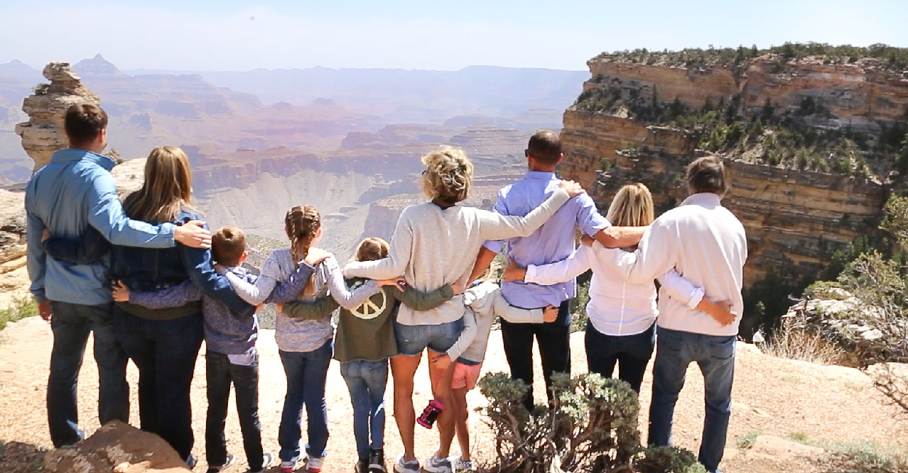 A group of adults and children stand at the edge of the Grand Canyon.