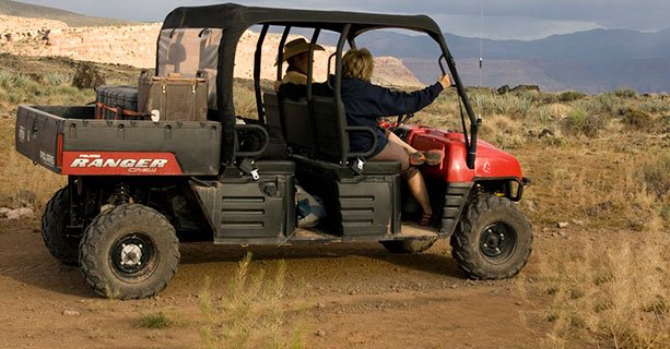 A Polaris Ranger vehicle carrying two passengers.