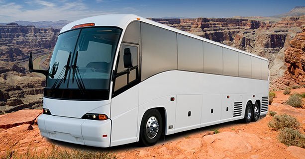 A large motorcoach with Grand Canyon scenery behind it.