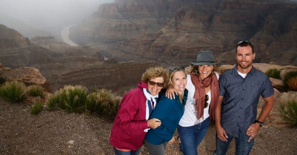 A family poses together in front of the Grand Canyon and the Colorado River.