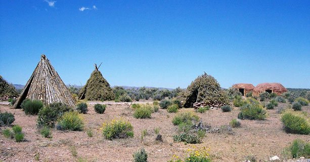 Traditional Native American dwellings surrounded by desert scenery.