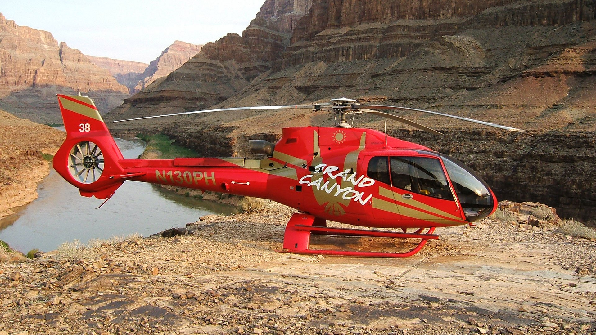 An EC-130 helicopter landed at the bottom of the Grand Canyon with the Colorado River in the background.