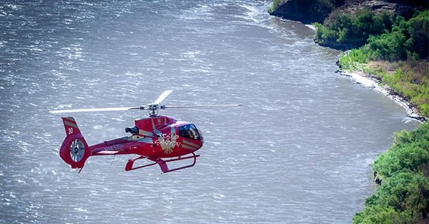 A helicopter flying over the Colorado River at the bottom of the Grand Canyon.