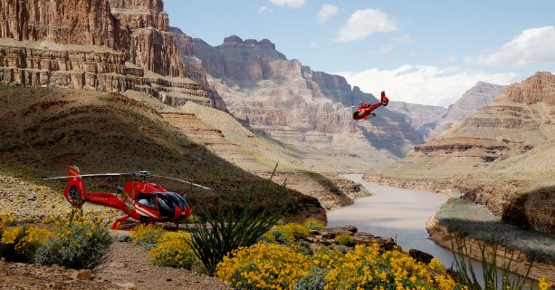 A helicopter landed at the bottom of the Grand Canyon and another taking off.