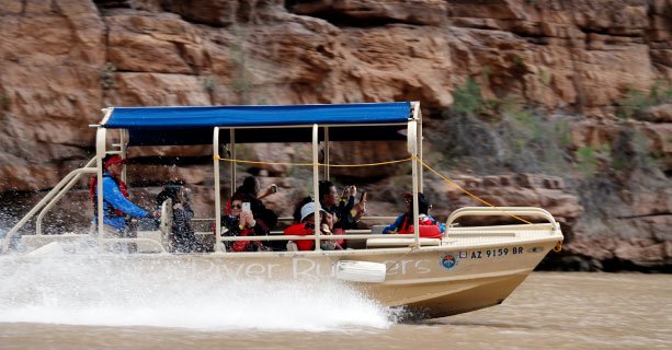 A pontoon boat filled with passengers sails down the Colorado River.