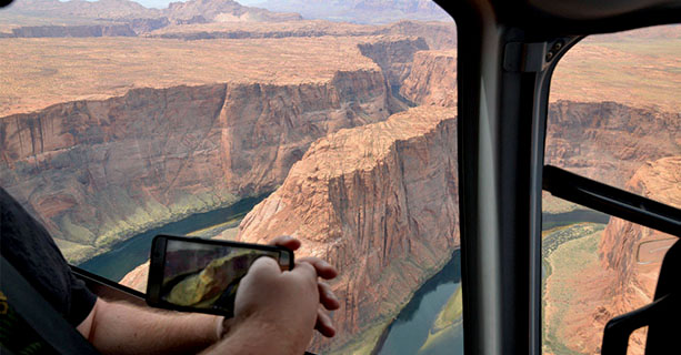 A passenger photographs a desert scene on their phone.