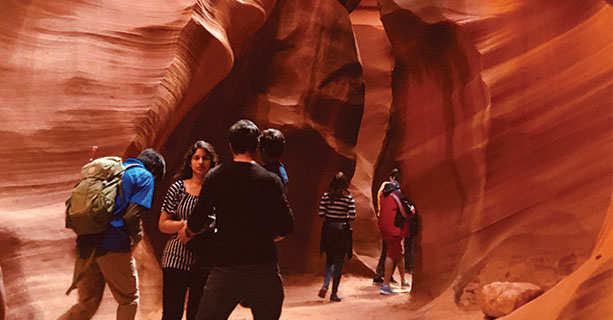 Groups of people stand inside a slot canyon.