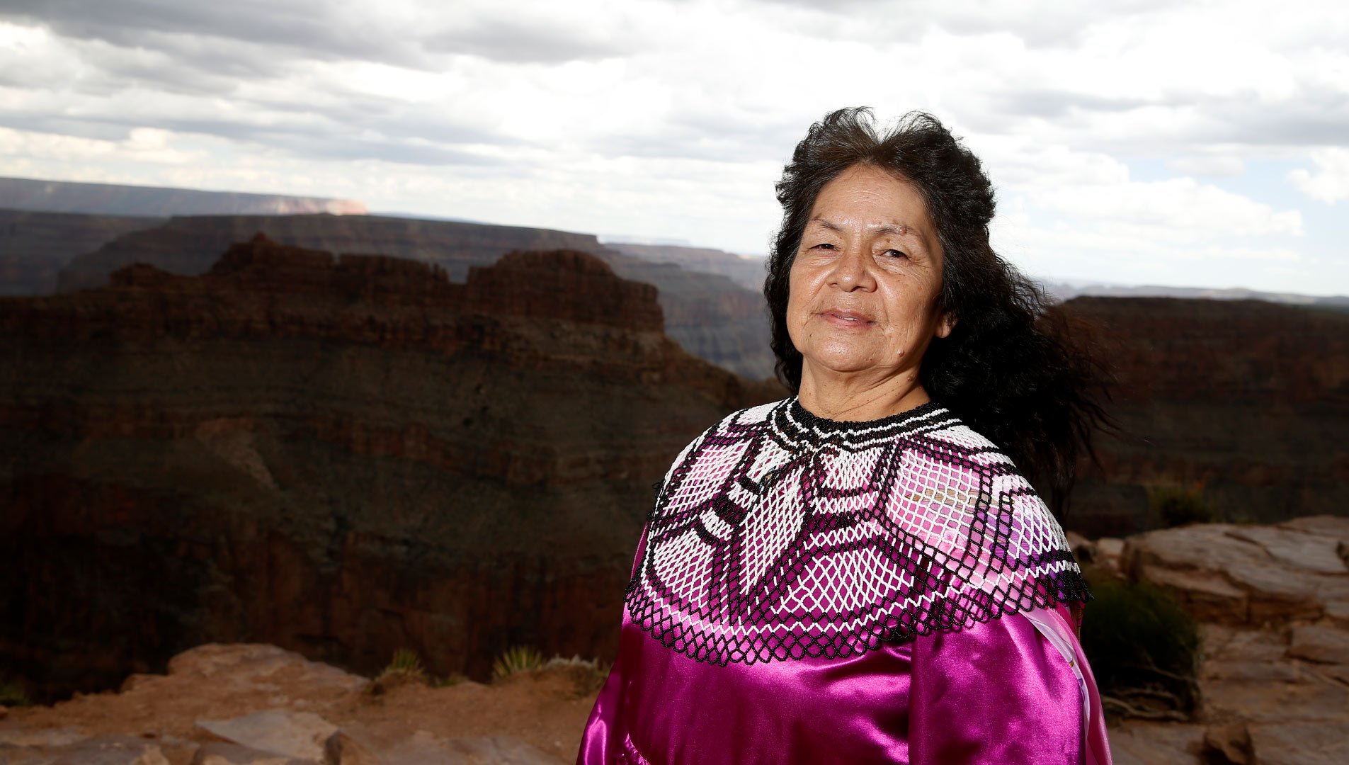 A Hualapai woman wearing traditional garb with the Grand Canyon in the background.