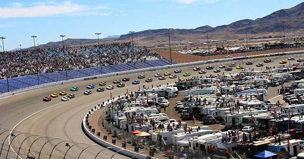 Several cars race around the curve of a track.