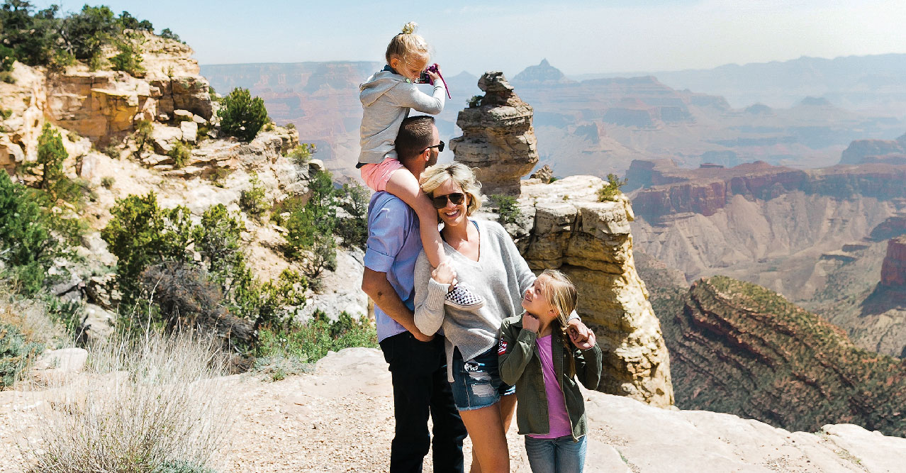 A family enjoying a moment together at the edge of the Grand Canyon.