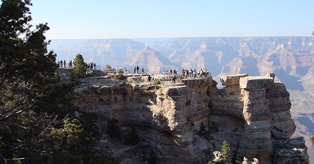 Visitors stand on a rocky overlook at the Grand Canyon National Park.