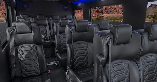 The interior of a Sprinter vehicle, including rows of black leather seats.