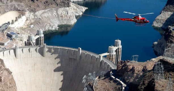 A helicopter soars over the Hoover Dam and Colorado River.