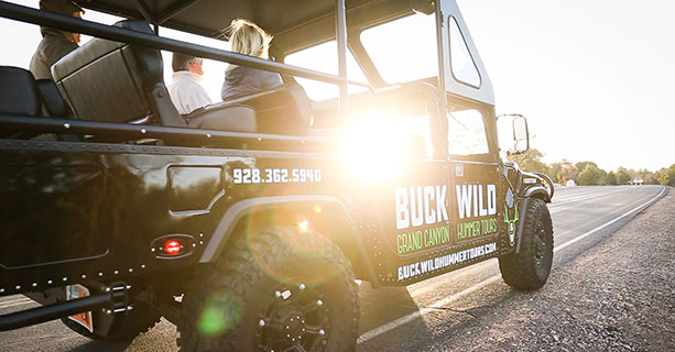 A touring Hummer vehicle setting off at sunset.