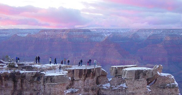 Guests on a snow-capped overlook of the South Rim of the Grand Canyon.