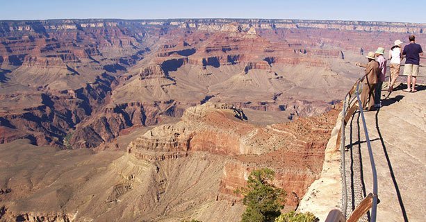 A group of sightseers stand at the edge of the Grand Canyon.