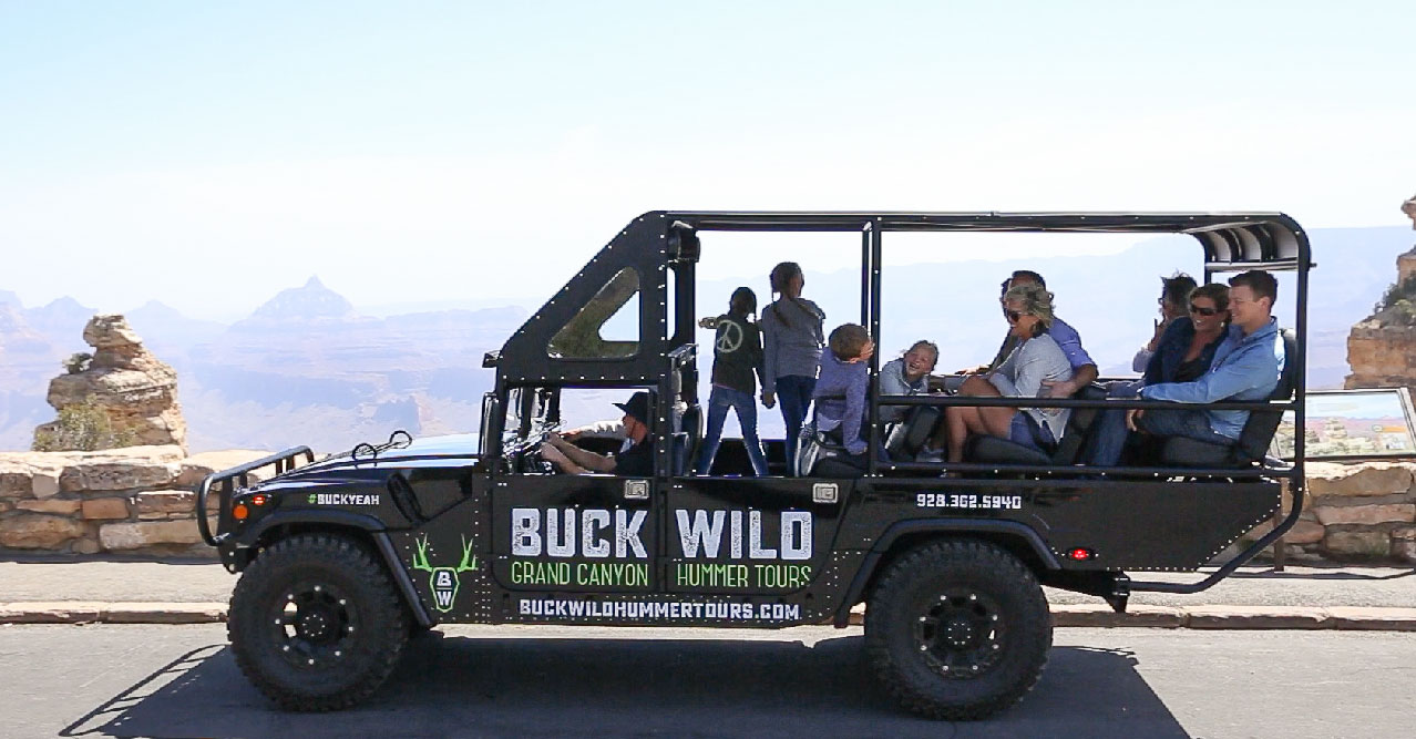 Passengers sit aboard an open-air touring Hummer.