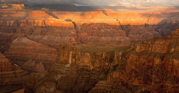 A Grand Canyon landscape, shaded by a cloudy sky.