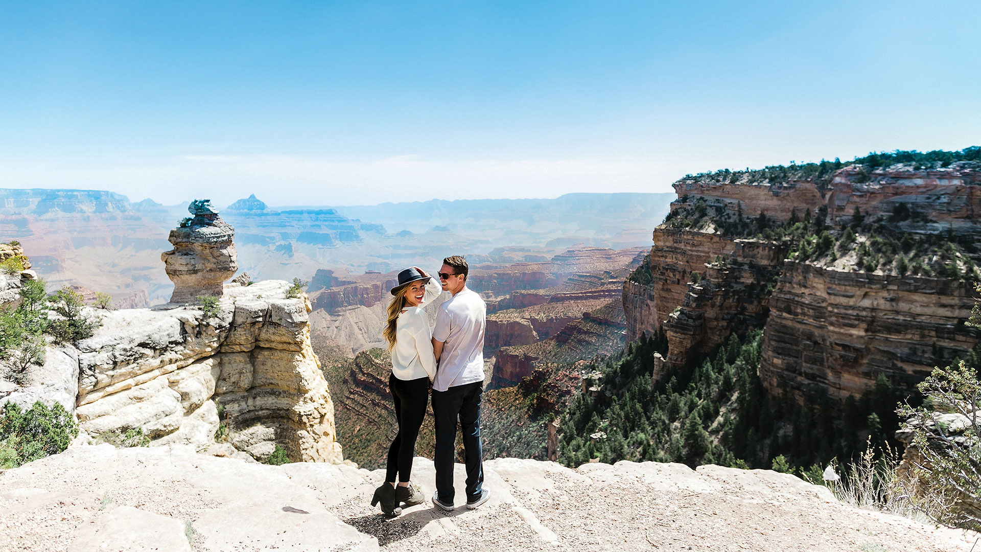 A couple poses at the edge of a Grand Canyon lookout point.