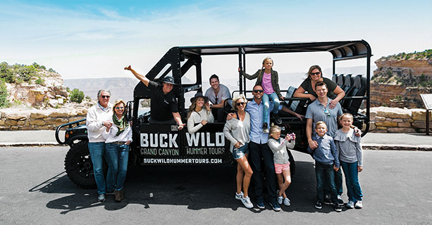 Passengers stand in front of a touring Hummer vehicle at the Grand Canyon National Park.