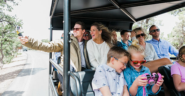 A family aboard a Hummer vehicle take photos of the passing scenery.