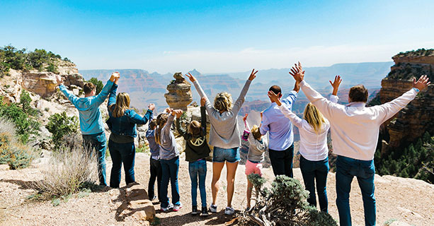 A family poses excitedly at a Grand Canyon viewpoint.