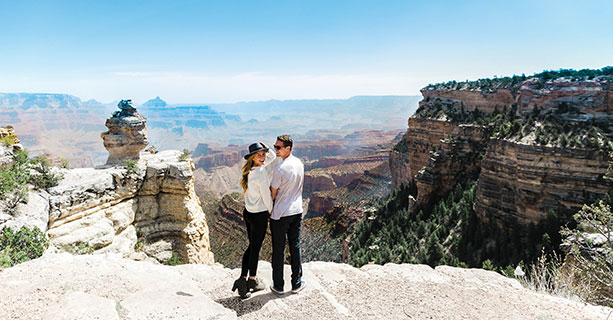 A couple poses together at the edge of the Grand Canyon.