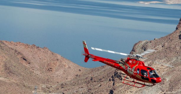 A Bell helicopter hovering over a crystal clear Lake Mead.