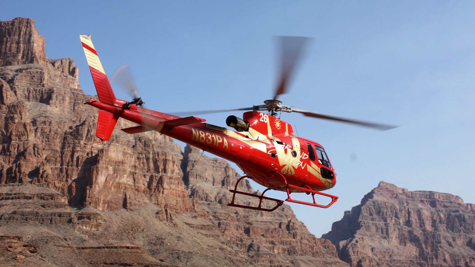 A red helicopter flies through the Grand Canyon West.