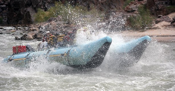 A raft splashes through some Colorado River rapids.