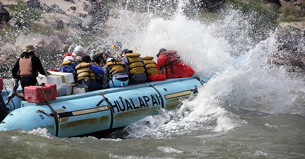 Passengers aboard a raft race through the rushing waters of the Colorado River.